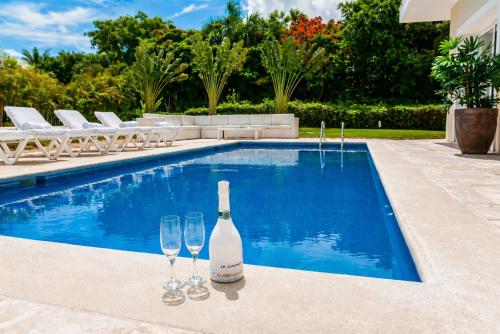 a bottle of wine and two wine glasses next to a swimming pool at Special offer! Villa Bueno with private pool&beach in Punta Cana