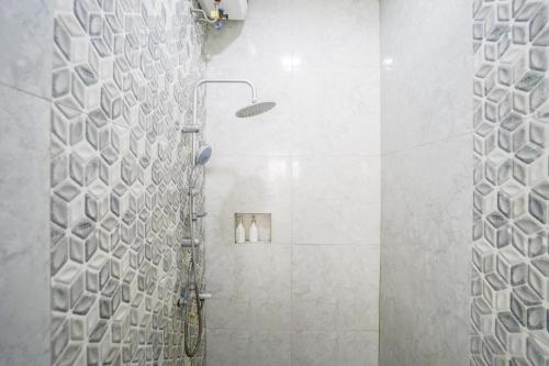 a bathroom with a shower with white tiles at Urbanview Hotel Nimara Ngawi by RedDoorz in Ngawi