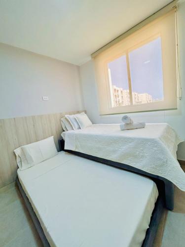 two beds in a small room with a window at Capriela Serena del Mar in Cartagena de Indias