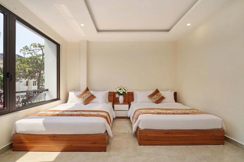 two beds in a room with a window at Hotel Duy Phương 2 in Da Lat