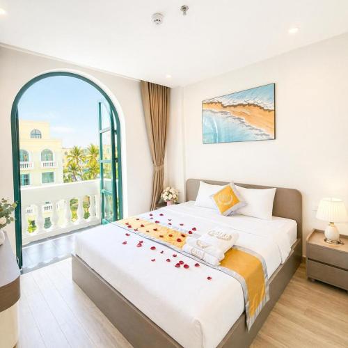 a bedroom with a large bed and a large window at LALU Hotel in Phú Quốc
