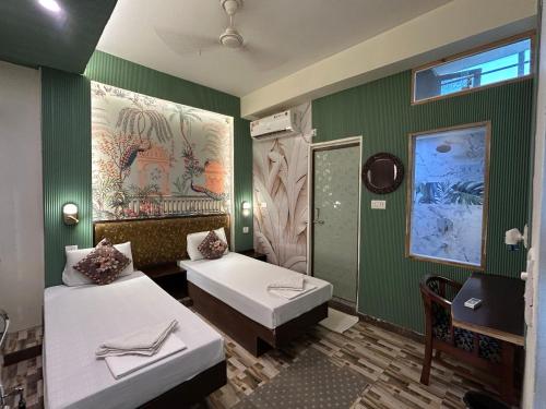 a green room with two beds and a mirror at Max Guest House in Agra