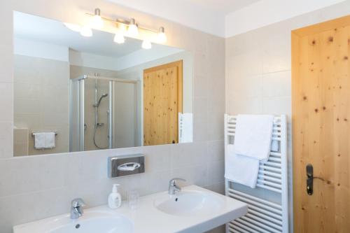 a bathroom with two sinks and a large mirror at Hotel Falken in Falzes