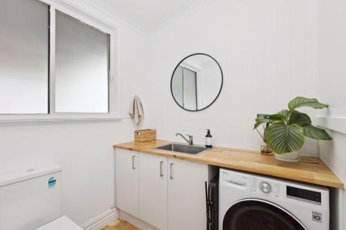 a laundry room with a sink and a washing machine at Barnard Bungalow in Bendigo