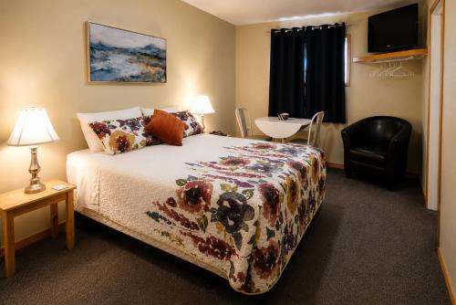 a bedroom with a bed and a chair and a table at NEWCASTLE COUNTRY INN in Drumheller