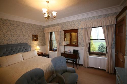 a bedroom with a bed and a chair and a window at West Acre House in Alnwick