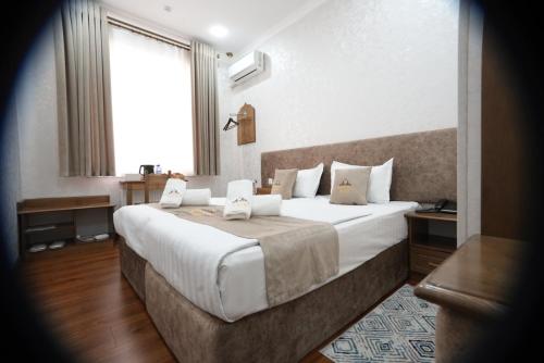 a bedroom with a large bed with white sheets and a window at Shergiron PLAZA in Bukhara