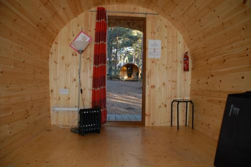 a room with a wooden wall with a doorway at Camping Pod Heaven in Brackla