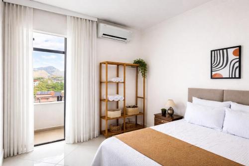a bedroom with a bed and a large window at Super Apt morada do Vale in Governador Valadares