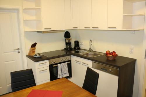 a kitchen with white cabinets and a sink and a table at Gästehaus Alte Bäckerei in Dachwig
