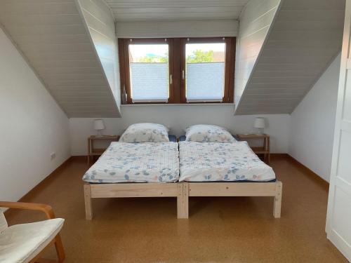 a bed in a room with two windows at Ferienwohnung-Loesch in Neuenburg am Rhein