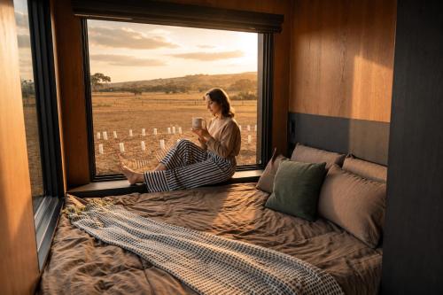 a woman sitting in a window looking out of a bed at AUTRA Resort Middleton in Middleton