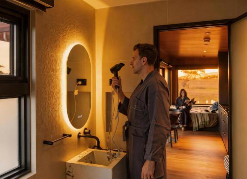 a man standing in front of a mirror with a hair dryer at AUTRA Resort Middleton in Middleton
