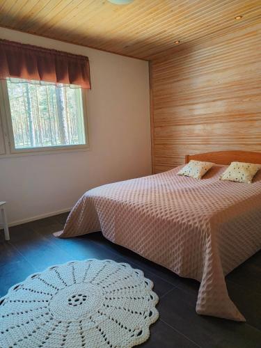 a bedroom with a bed and a window and a rug at Mökki Jyrkinkuja in Loimaa