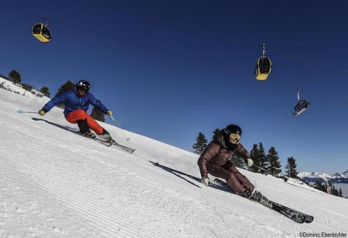 two people skiing down a snow covered slope with a ski lift at Haus Alpenfriede in Ramsau im Zillertal