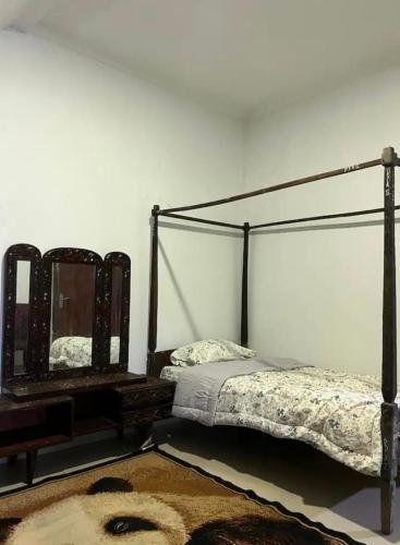 a bedroom with a bed and a mirror on the wall at Villa Murah Joglo Sariwangi in Cihanjuang 1