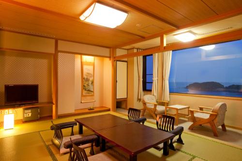 a living room with a table and chairs and a television at Resort Hills Toyohama Soranokaze in Toba