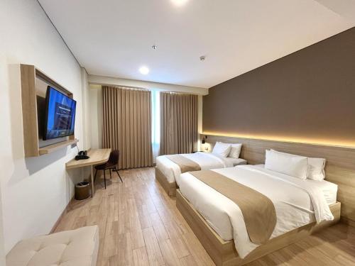 a hotel room with two beds and a television at Prime UMY Hotel Convention & Dormitory in Yogyakarta