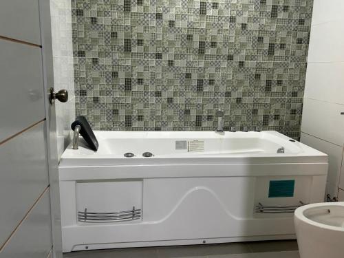 a white bath tub in a bathroom with a toilet at Three Bedrooms Comfort Zone Guesthouse in Bengcag