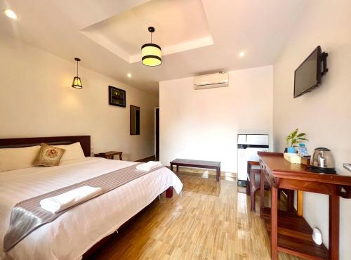 a bedroom with a bed and a desk in it at Monterey Angkor Boutique in Phum Pobos