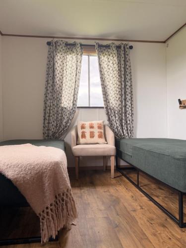 a bedroom with a bed and a chair and a window at Cwt Ieir in Ruthin
