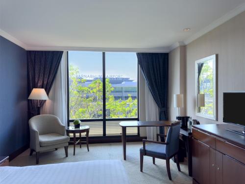 a hotel room with a bed and a desk and a large window at Hyatt Regency Bangkok Suvarnabhumi Airport in Lat Krabang