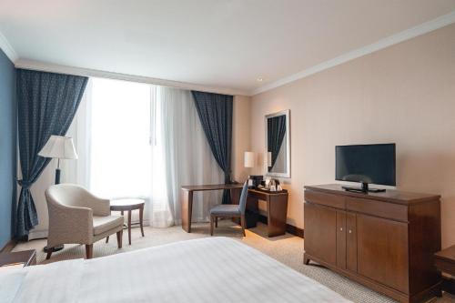 a hotel room with a bed and a television and a desk at Hyatt Regency Bangkok Suvarnabhumi Airport in Lat Krabang