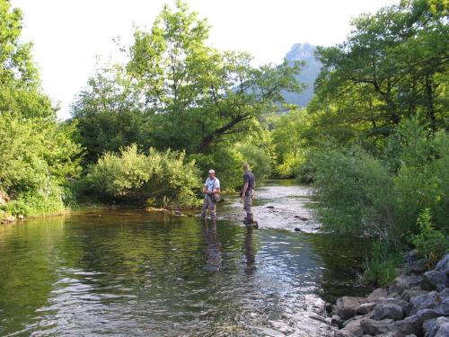 two people walking across a stream in the water at Holiday House Sobol in Kuželj