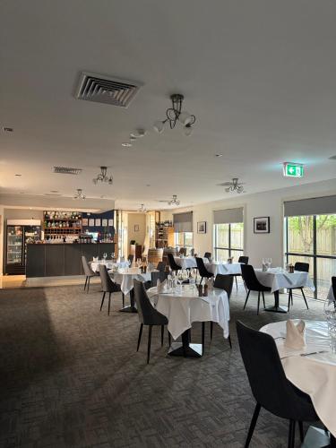 a dining room with white tables and chairs at Bairnsdale International in Bairnsdale