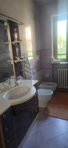 a bathroom with two sinks and a toilet and a window at Residenza dei pini lacchiarella in Lacchiarella
