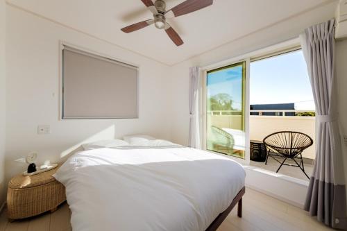 a white bedroom with a bed and a large window at Halema in Ichinomiya