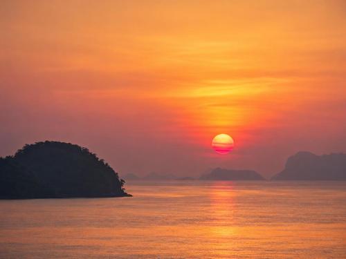 a sunset over a body of water with an island at Reen Run Sunset Private Pool Villa in Ko Phangan