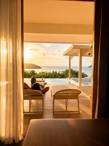 a person sitting in a chair on the balcony of a house at Reen Run Sunset Private Pool Villa in Ko Phangan