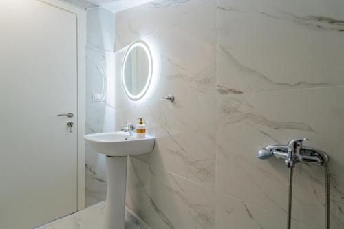 a white bathroom with a sink and a shower at SithoniaRS Sea Nomad Luxury Maisonette in Nikiti