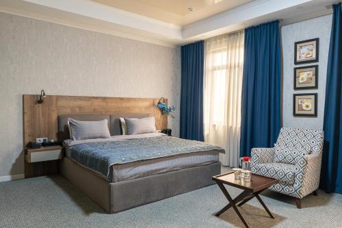 a bedroom with a bed and a chair at Onyx Hotel Bishkek in Bishkek