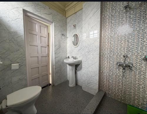a bathroom with a toilet and a sink and a door at Apsara Guest House, Peaceful Area in Central Shillong in Shillong