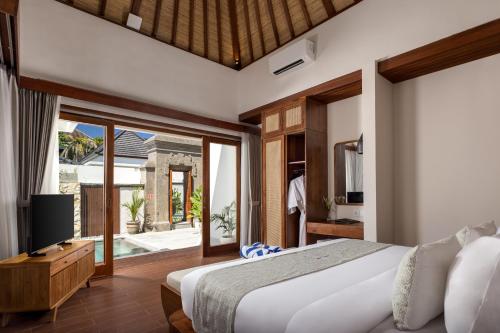 a bedroom with a bed and a sliding glass door at The Prime Seminyak by Kanaya Hospitality in Seminyak