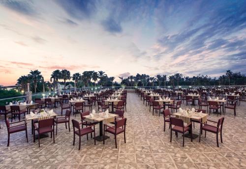 un ristorante con tavoli e sedie sulla spiaggia di Delphin BE Grand Resort a Lara