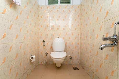 a bathroom with a toilet and a toilet paper dispenser at ILLIKKALAM Lakeside Cottages Kumarakom Kerala in Kumarakom