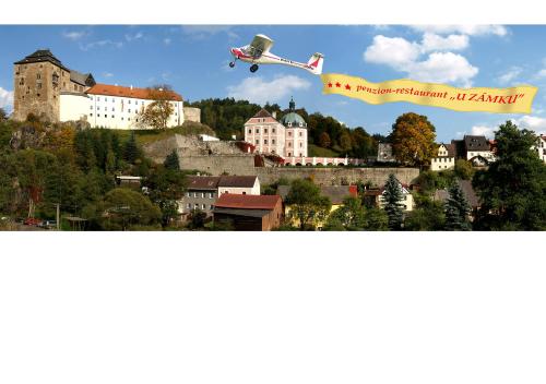 an airplane is flying over a city with a castle at Penzion - Restaurant U Zámku in Bečov nad Teplou