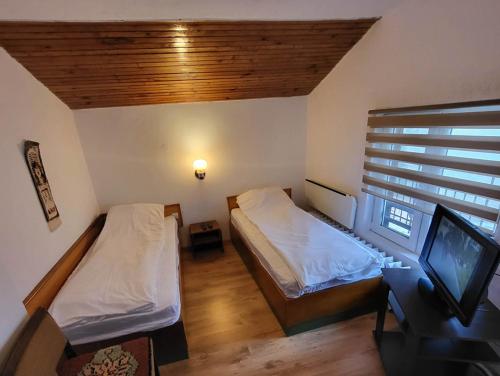 a small room with two beds and a television at Вила Беевски in Gela