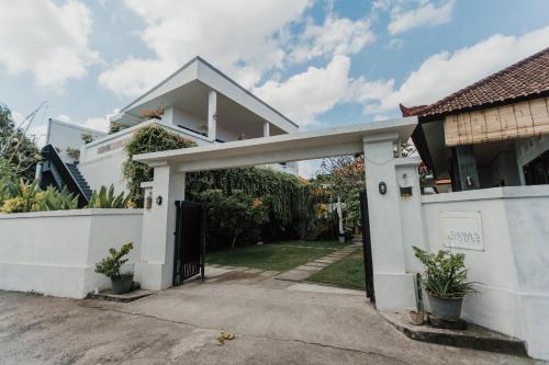 a white house with a gate and a driveway at Dana's Kelating Guest House, Close to Kelating Beach in Tabanan