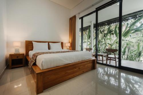 a bedroom with a bed and a large window at Dana's Kelating Guest House, Close to Kelating Beach in Tabanan
