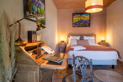 a bedroom with a bed and a desk with a laptop at Le Jardin Secret in Grignan