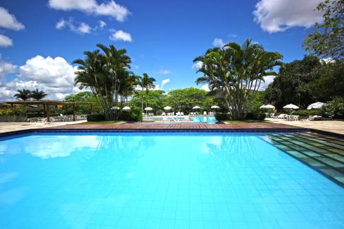 a large swimming pool with trees and umbrellas at Hotel Fazenda Portal de Gravatá in Gravatá