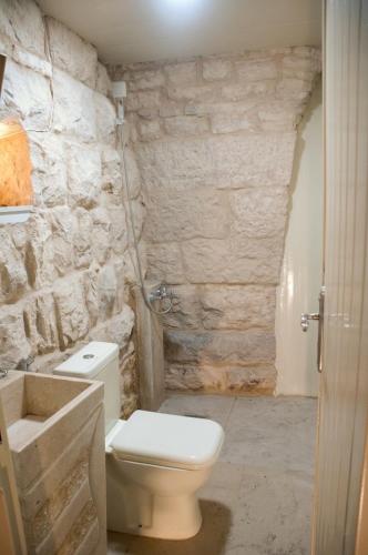 a bathroom with a toilet and a stone wall at Bayt Broud in Gharīfah