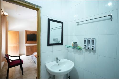 a white bathroom with a sink and a mirror at Jhumelo Homestay, Ukhimath in Ukhimath