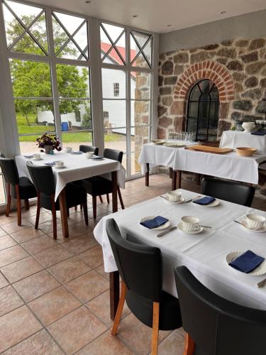 a restaurant with white tables and chairs and windows at Aamølle Gæstgiveri in Hadsund
