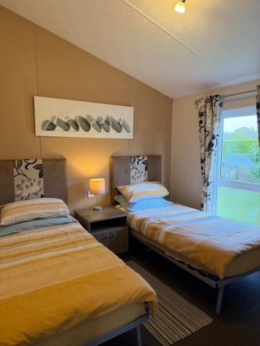 two beds in a room with a window at Southerness Holiday Home Cheri Sleeps 4 Mon-Fri Fri-Mon with Solway Holiday Homes in Mainsriddle