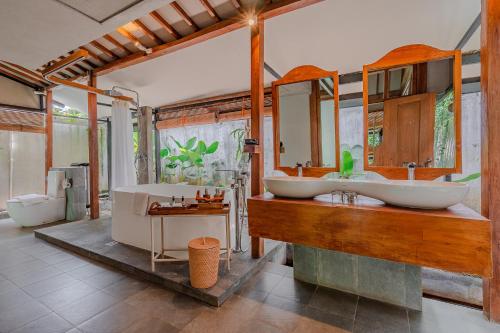 ein Badezimmer mit zwei Waschbecken und einer Badewanne in der Unterkunft Ayom Java Village Solo in Solo